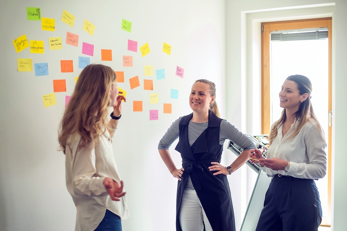 Teilnehmerinnen vor bunter Ideenwand im Workshop